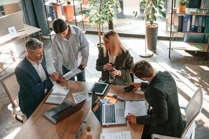 By the table ,with laptops. Top view. Group of business people are working in the modern office photo