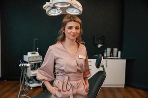 Doctor is, standing ,and smiling. In the stomatological cabinet photo