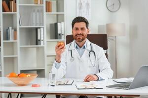 Holding an apple.. Doctor in formal clothes is working in the cabinet photo