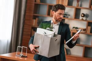 With a box of stuff in it. Businessman in formal clothes is working indoors photo