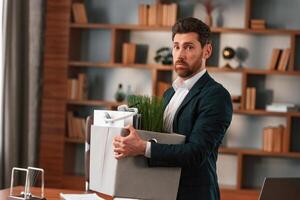 With a box of stuff in it. .Businessman in formal clothes is working indoors photo