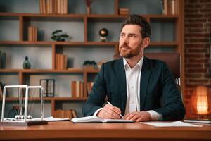 Writing down the ideas. Businessman in formal clothes is working indoors photo