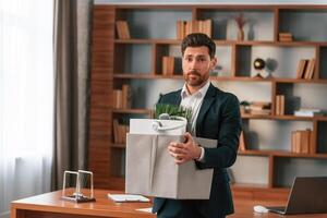 With a box, of stuff in it. Businessman in formal clothes is working indoors photo