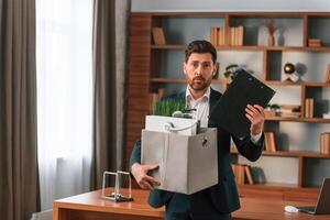 With a box of stuff ,in it. Businessman in formal clothes is working indoors photo