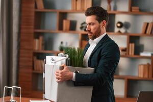 With, a box of stuff in it. Businessman in formal clothes is working indoors photo