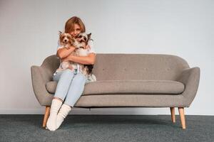Conception of care and love.. Woman is sitting on a sofa with two cute dogs photo