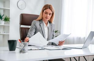 Doing, paperwork. Woman in business formal clothes is working in office photo