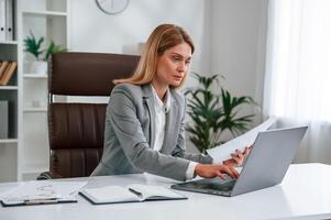 Doing paperwork.. Woman in business formal clothes is working in office photo