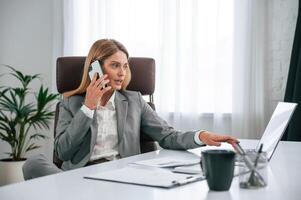 Talking ,by phone. Woman in business formal clothes is working in office photo