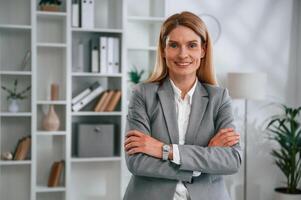 Standing with, arms crossed. Woman in business formal clothes is working in office photo