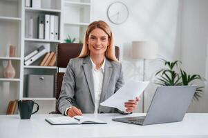 Doing paperwork. Woman in business formal clothes is working in office photo