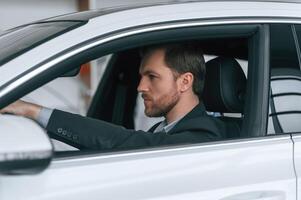 Serious, facial expression. Driving the car. Man in formal business clothes is sitting in the modern automobile photo