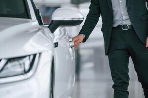 Close, up, view of man in suit that is opening the door of the new white colored automobile photo