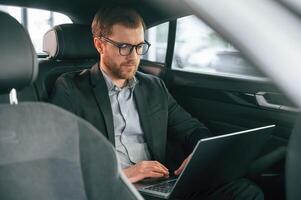 Man in formal ,business clothes is sitting in the modern automobile photo