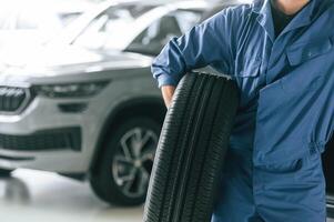 Tire ,replacement concept. Man in blue uniform is working in the car service photo