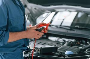Testing,, breakage by using electrical terminals. Man in blue uniform is working in the car service photo