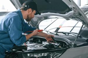 Testing ,breakage by using electrical terminals. Man in blue uniform is working in the car service photo