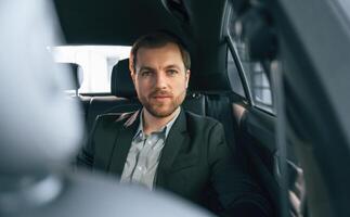 In comfortable, modern automobile. Man in formal business clothes photo