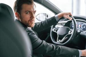 Driving the, car. Man in formal ,business clothes is sitting in the modern automobile photo