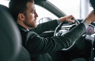 Driving the, car. Man in formal business clothes is sitting in the modern automobile photo