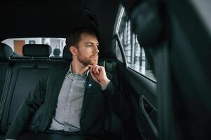 Man in formal business, clothes is sitting in the modern automobile photo