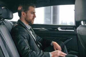 Portrait ,of man in formal business clothes that is sitting in the modern automobile photo