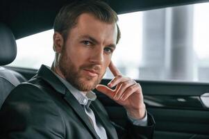 Portrait of man in formal business clothes that, is, sitting in the modern automobile photo