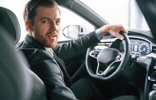 Portrait of man in formal business clothes that is sitting in the modern automobile photo