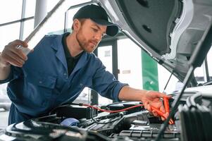 Testing ,breakage, by using electrical terminals. Man in blue uniform is working in the car service photo