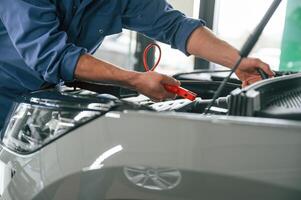 Testing, breakage by using electrical, terminals. Man in blue uniform is working in the car service photo