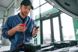 Testing, breakage by using electrical ,terminals. Man in blue uniform is working in the car service photo