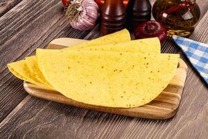 Three tortillas on a wooden cutting board with vegetables and spices photo
