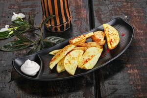 A black plate with some potatoes and a drink photo