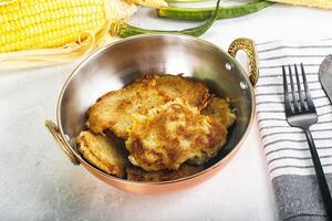 A bowl of corn on the cob with potatoes and a fork photo