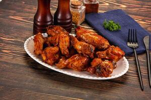 A plate of wings on a table with a napkin and fork photo