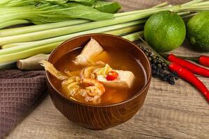 A bowl of soup with a bowl of vegetables and a lime photo