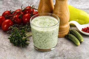 A glass of green smoothie with tomatoes, cucumbers and other vegetables photo