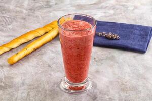 A glass of smoothie with a napkin and a baguette photo
