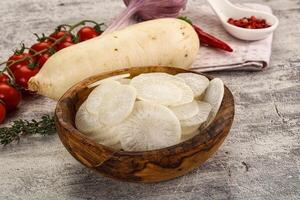 A wooden bowl filled with sliced vegetables and herbs photo