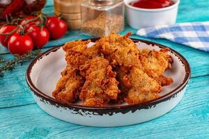 A bowl of fried chicken on a table with tomatoes and ketchup photo