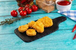 Fried chicken nuggets on a black board with spices and tomatoes photo
