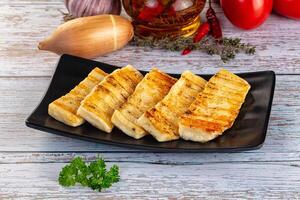 Grilled tofu on a black plate with vegetables and spices photo