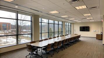 Modern conference room with large windows overlooking a serene landscape, equipped with a long table and ergonomic chairs, perfect for meetings and presentations. photo