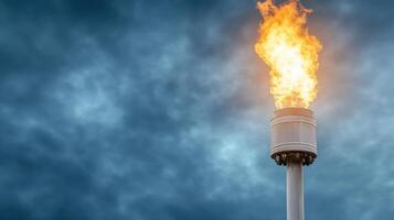 Flare tower at oil refinery burning excess gases against dramatic sky photo