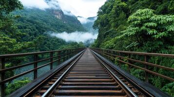 railway track stretches through lush green landscape, surrounded by mountains and mist photo