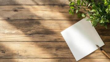 blank sheet of paper and quill on wooden table with greenery photo