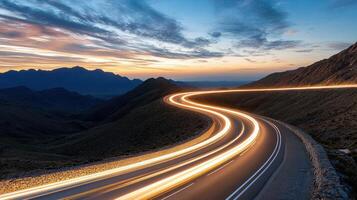 surreal highway winding through mountains at sunset, showcasing light trails photo
