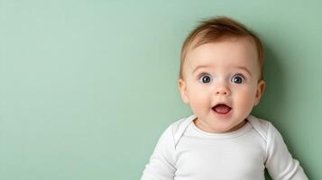 baby with curious gaze and surprised expression on pastel green background photo