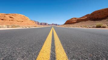 quiet open desert road with faded yellow lines leading to distant mountains photo