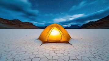 glowing tent stands on cracked salt flat under starry sky photo